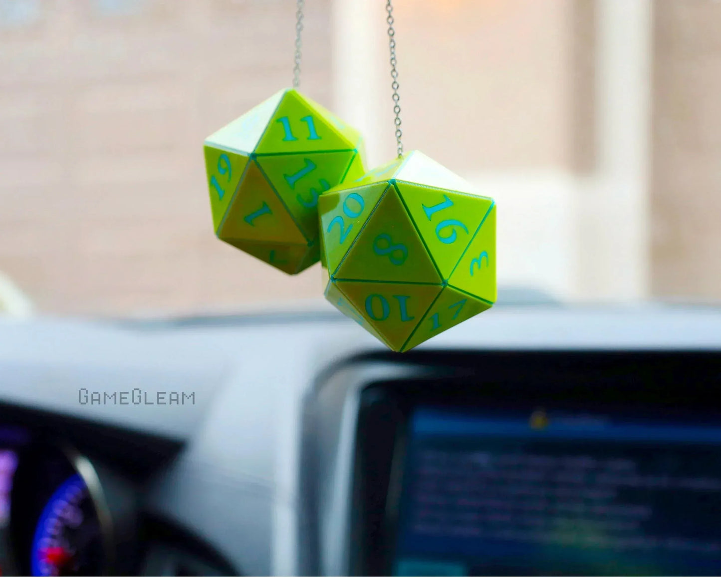 Green and blue twenty-sided dice car charm hanging from rearview mirror