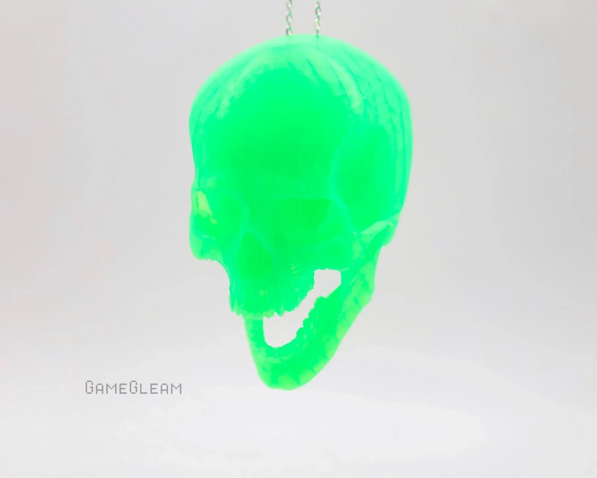 Neon green resin skull charm hanging from a chain, minimalist background