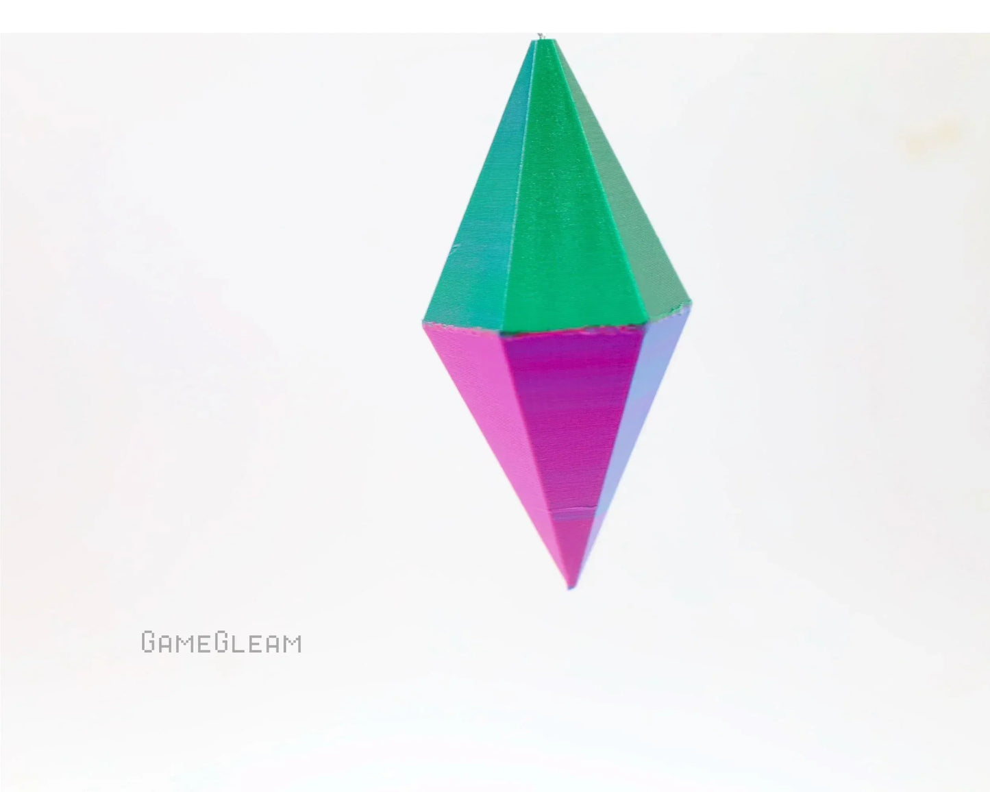 Colorful geometric prism-shaped car charm with green and pink segments, on white background