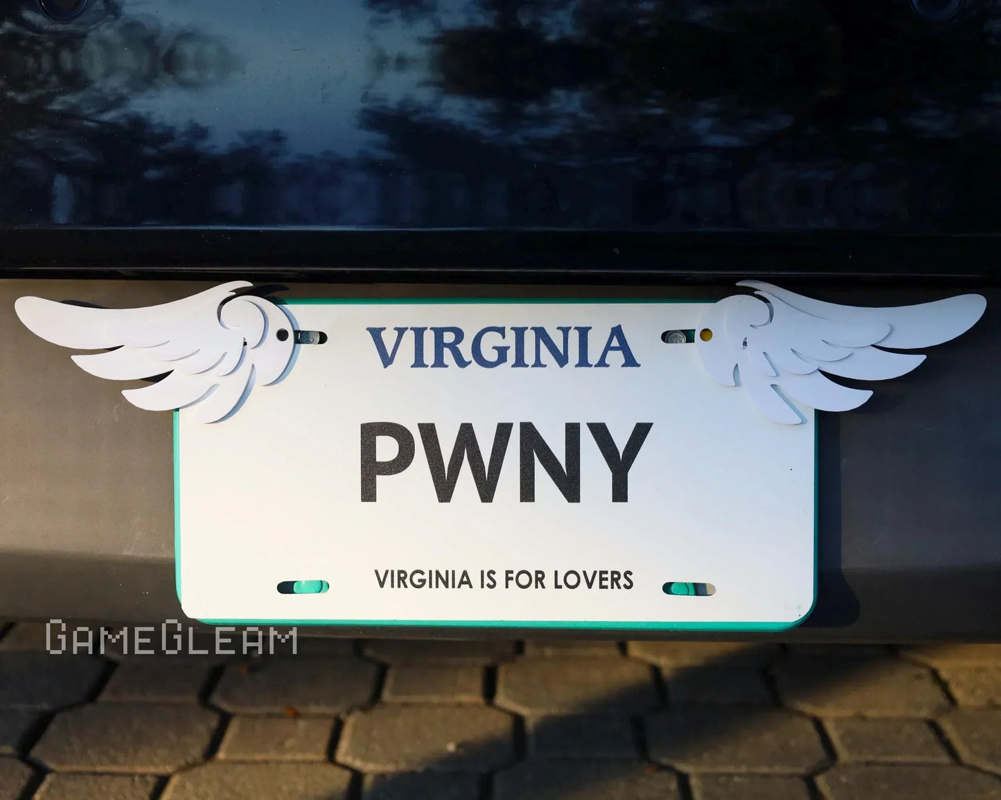 Virginia license plate with custom white winged decorations on a car bumper
