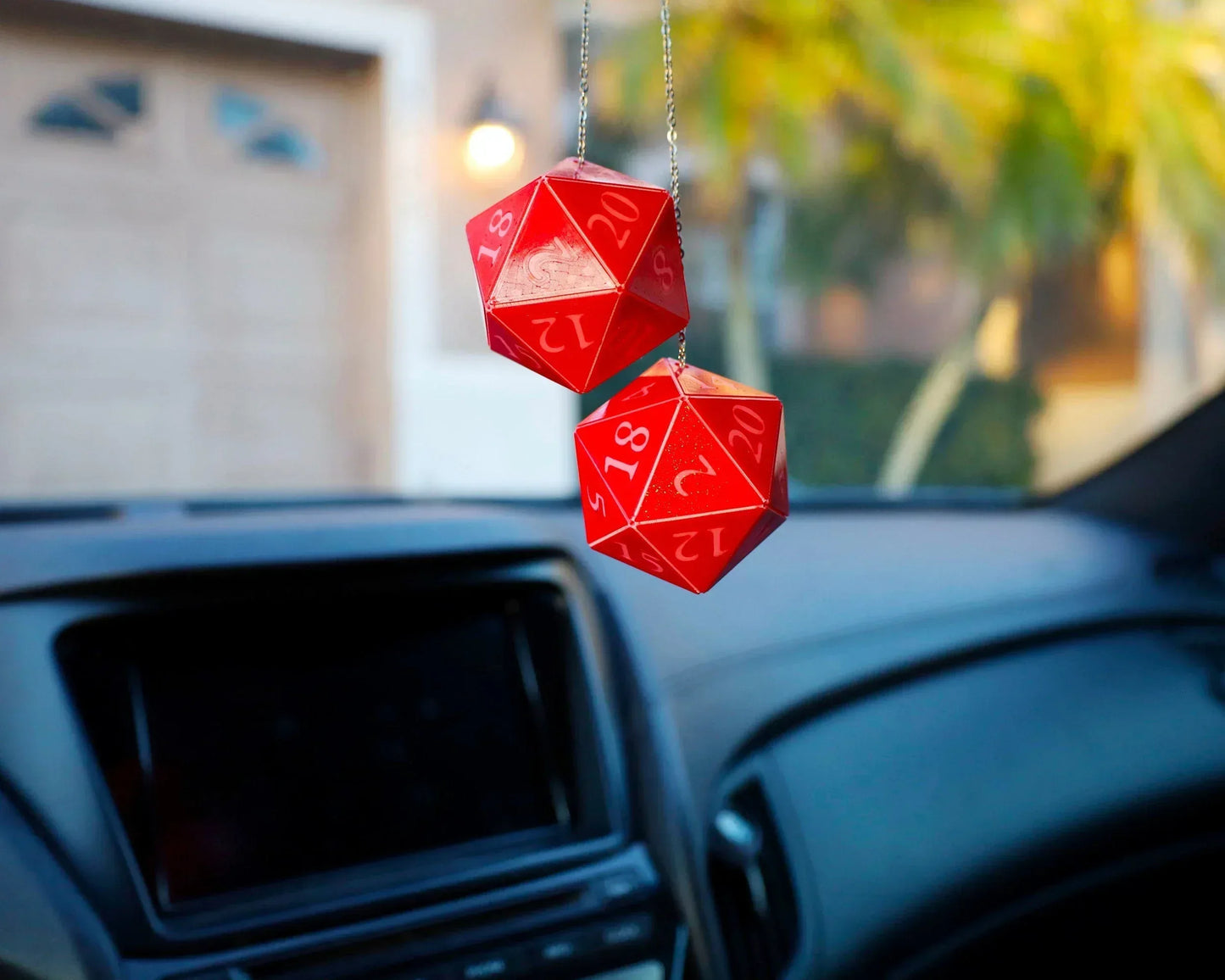 Red twenty-sided dice car charms hanging from rearview mirror in a car interior