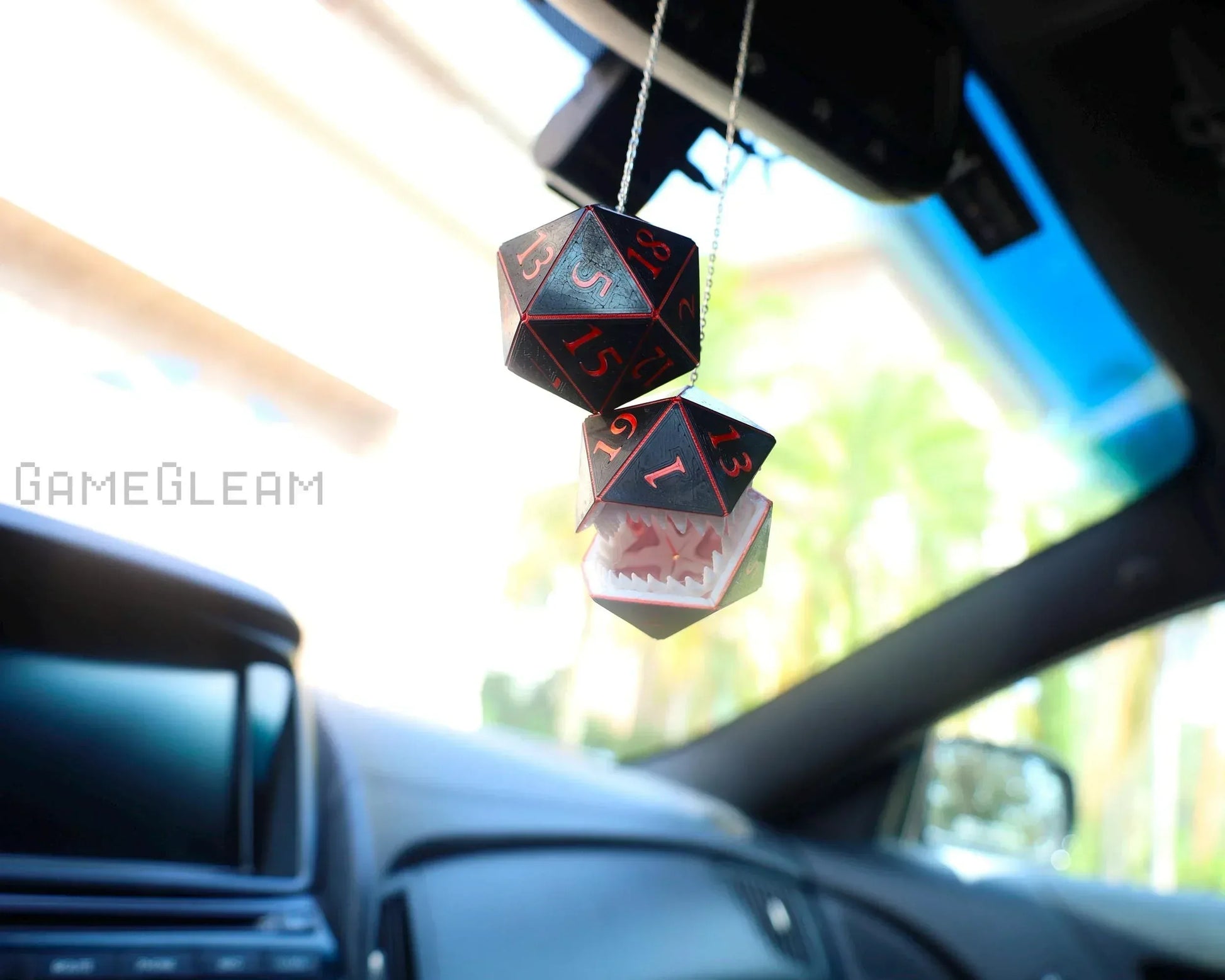 Black and red twenty-sided dice and mimic charm hanging from car rearview mirror