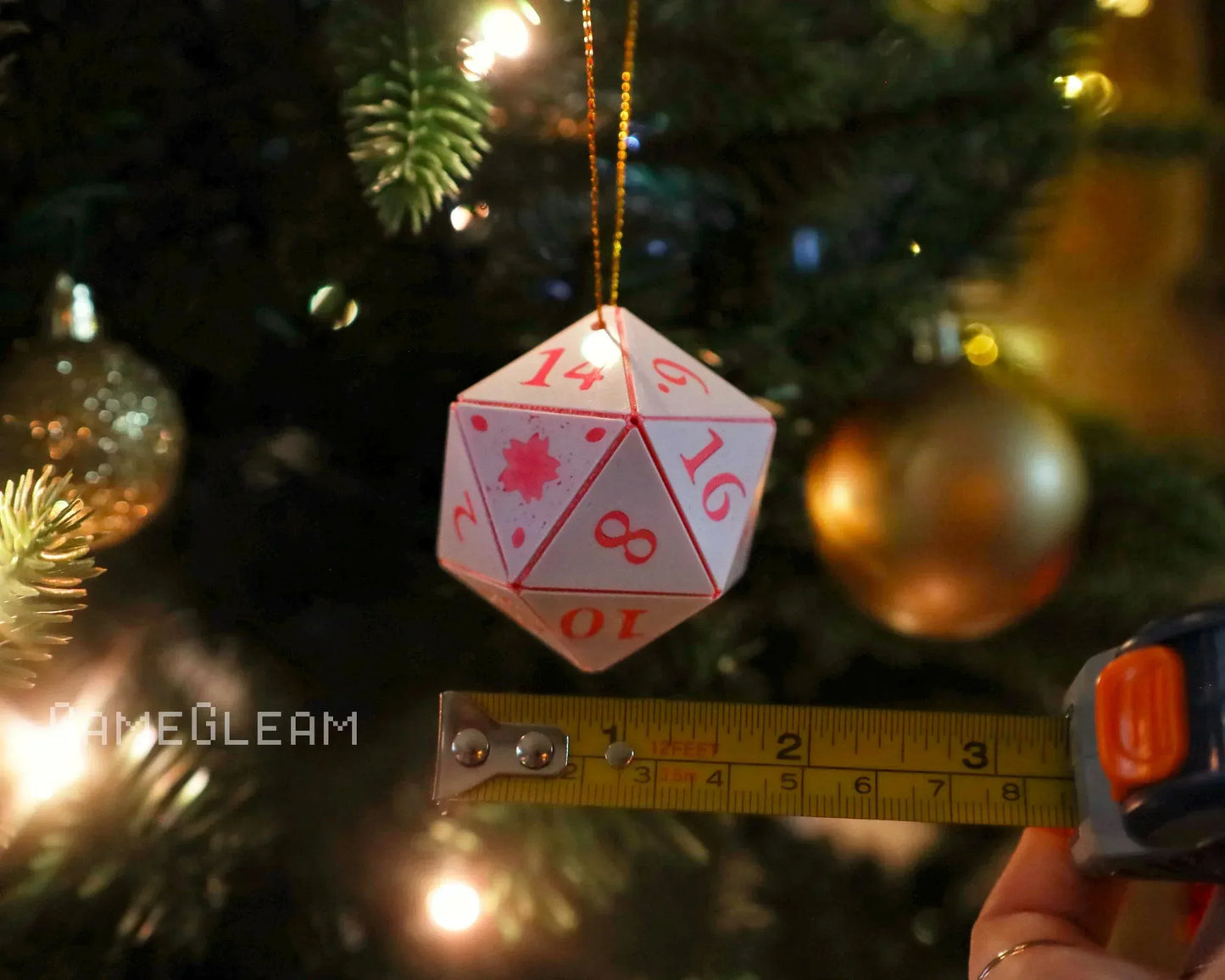 White 20-sided gaming dice ornament on Christmas tree, measured with tape, festive lights