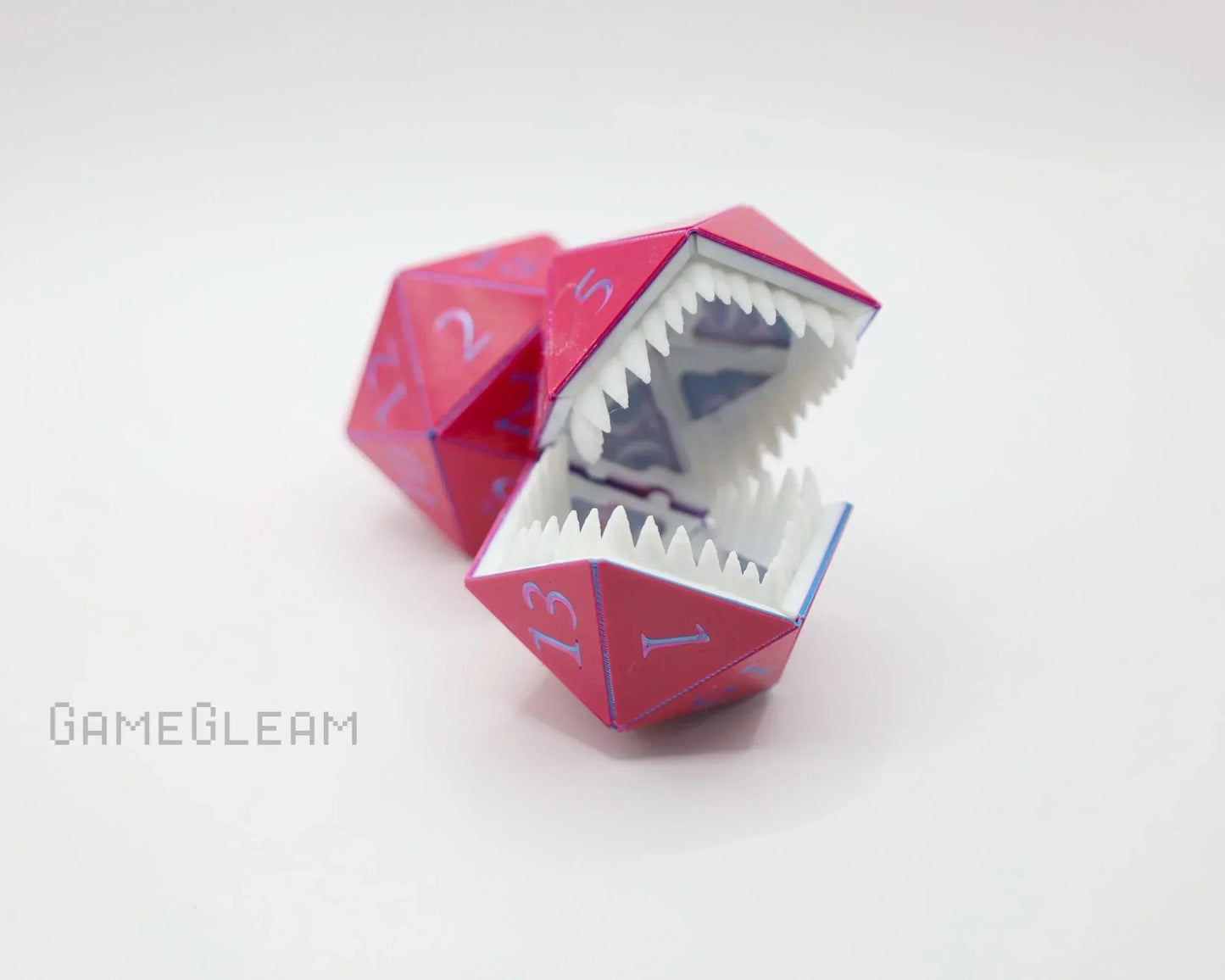 Pink polyhedral dice with sharp monster teeth, novelty gamer accessory on white background.