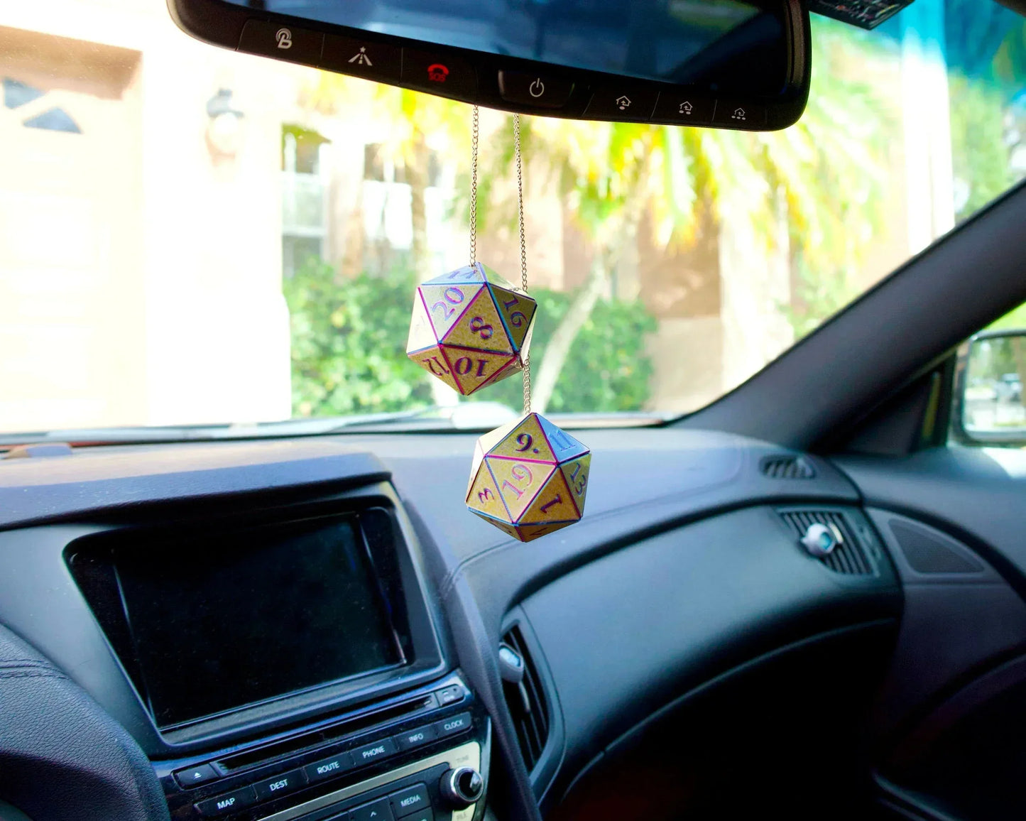 Holographic twenty-sided dice car charm hanging from rearview mirror in vehicle interior