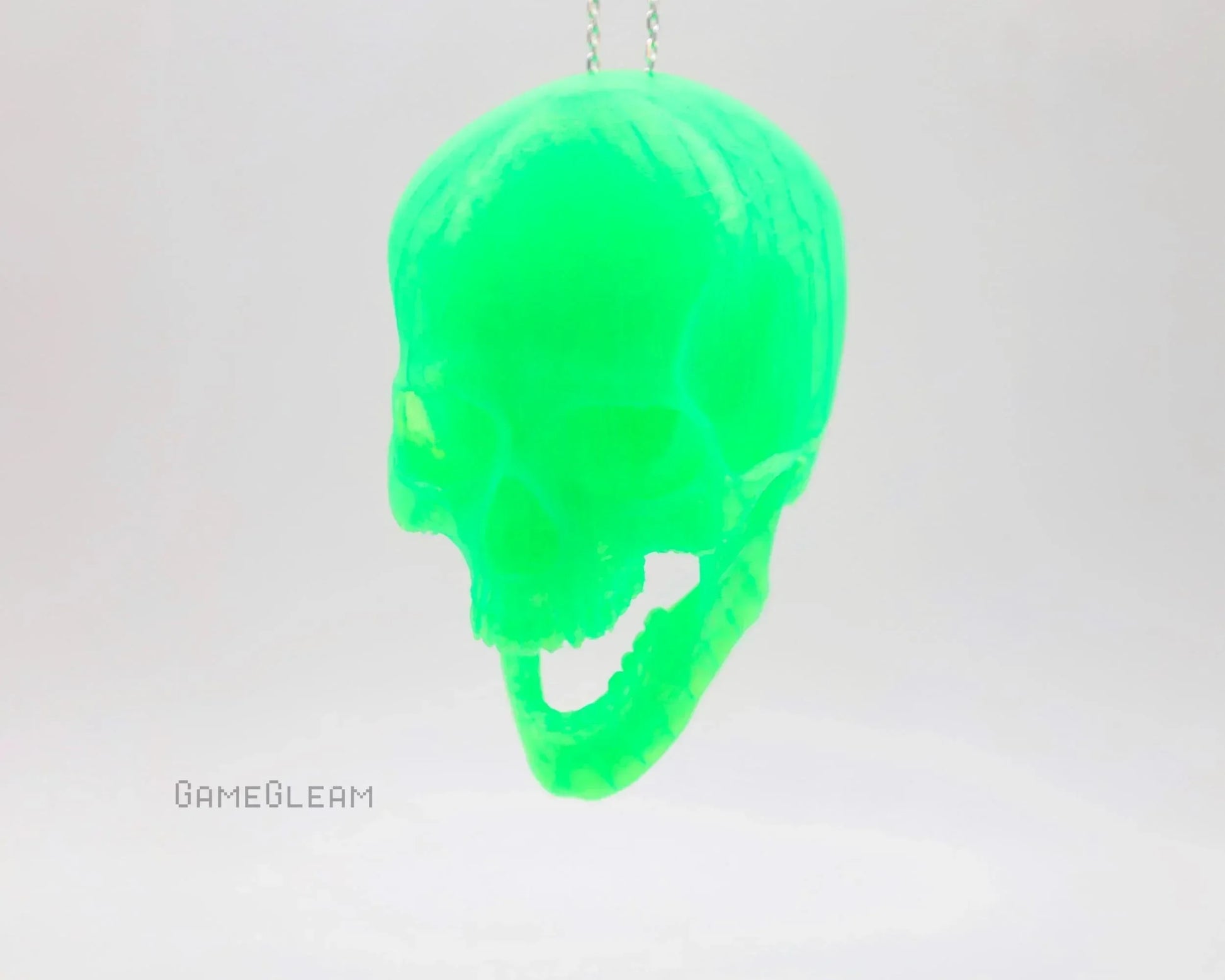Neon green resin skull car charm on a chain, handmade and suspended against white background