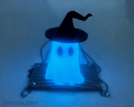 Glowing blue ghost charm with witch hat sitting on a swing, unique handmade accessory