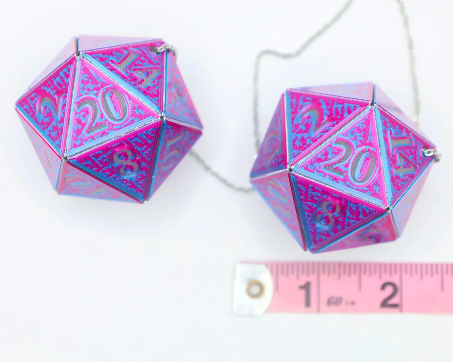 Holographic pink and blue twenty-sided dice car charm with measuring tape for scale