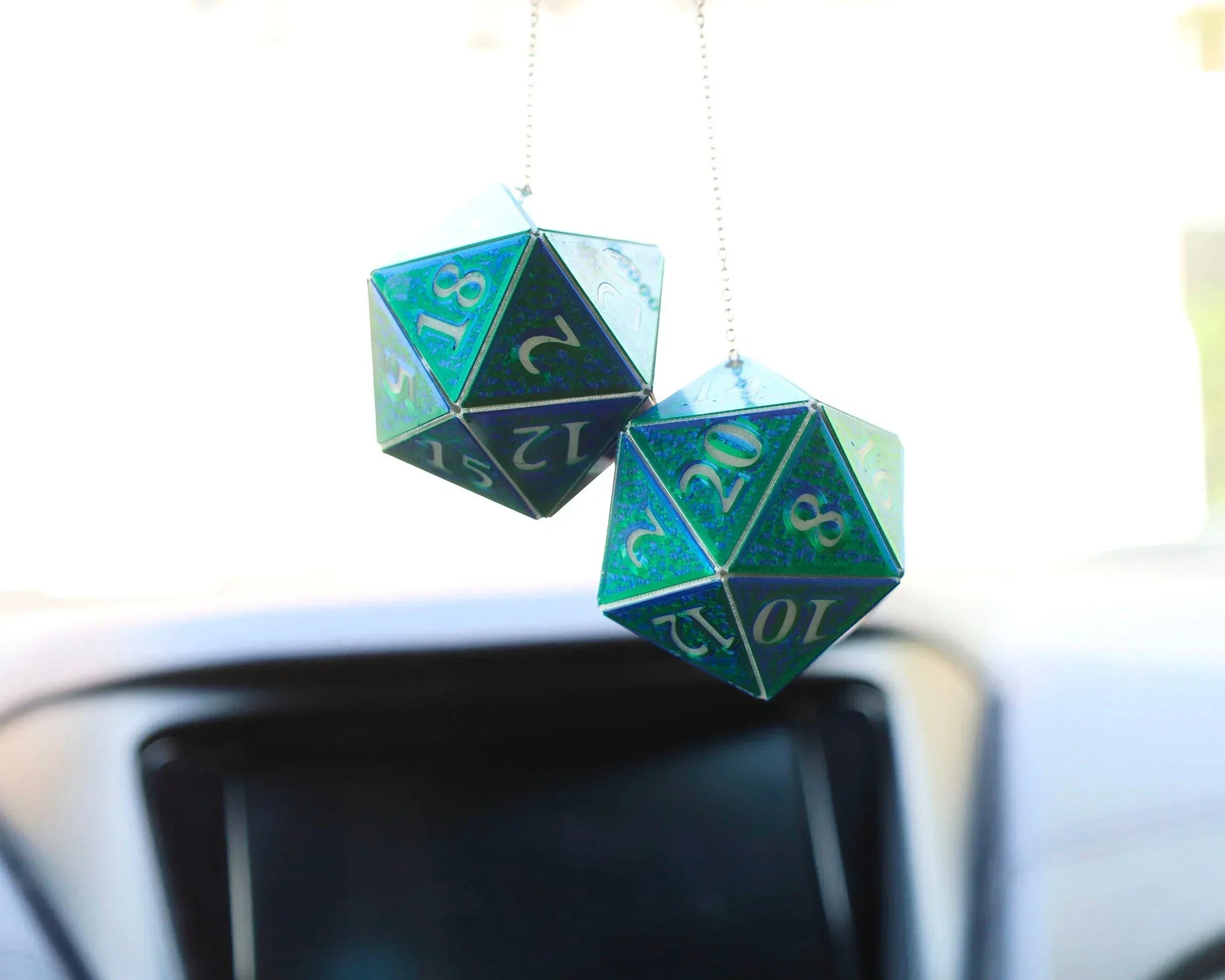 Holographic blue green 20-sided dice car charm hanging from rearview mirror