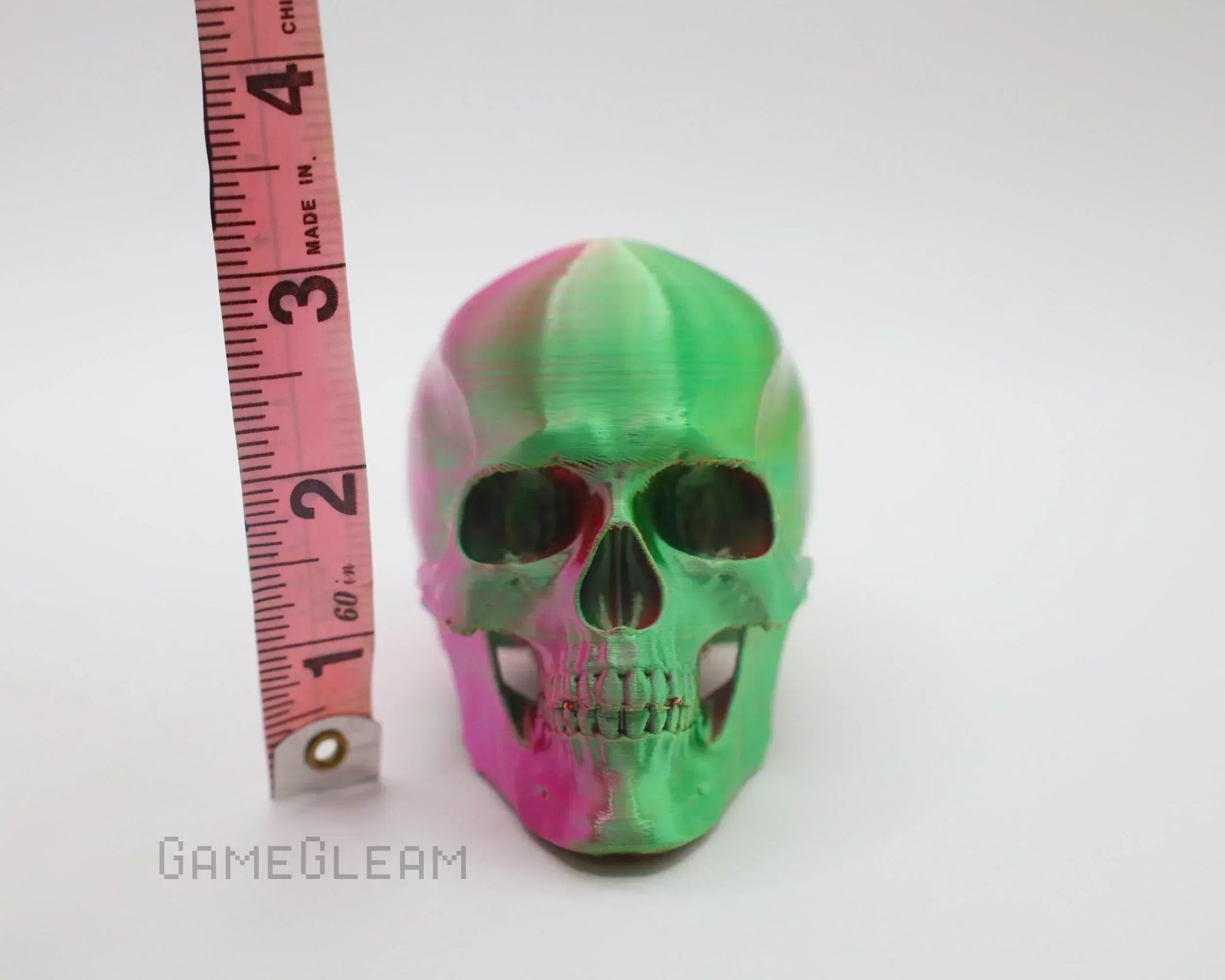 Handmade green and pink resin skull with measuring tape for size reference