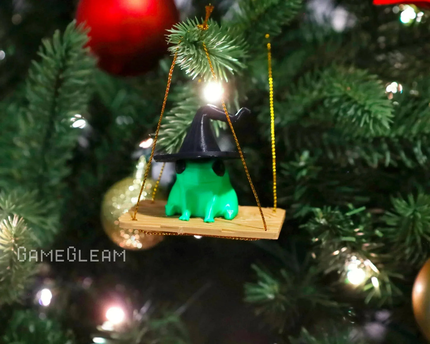 Green frog ornament with wizard hat on a wooden swing hanging from a Christmas tree