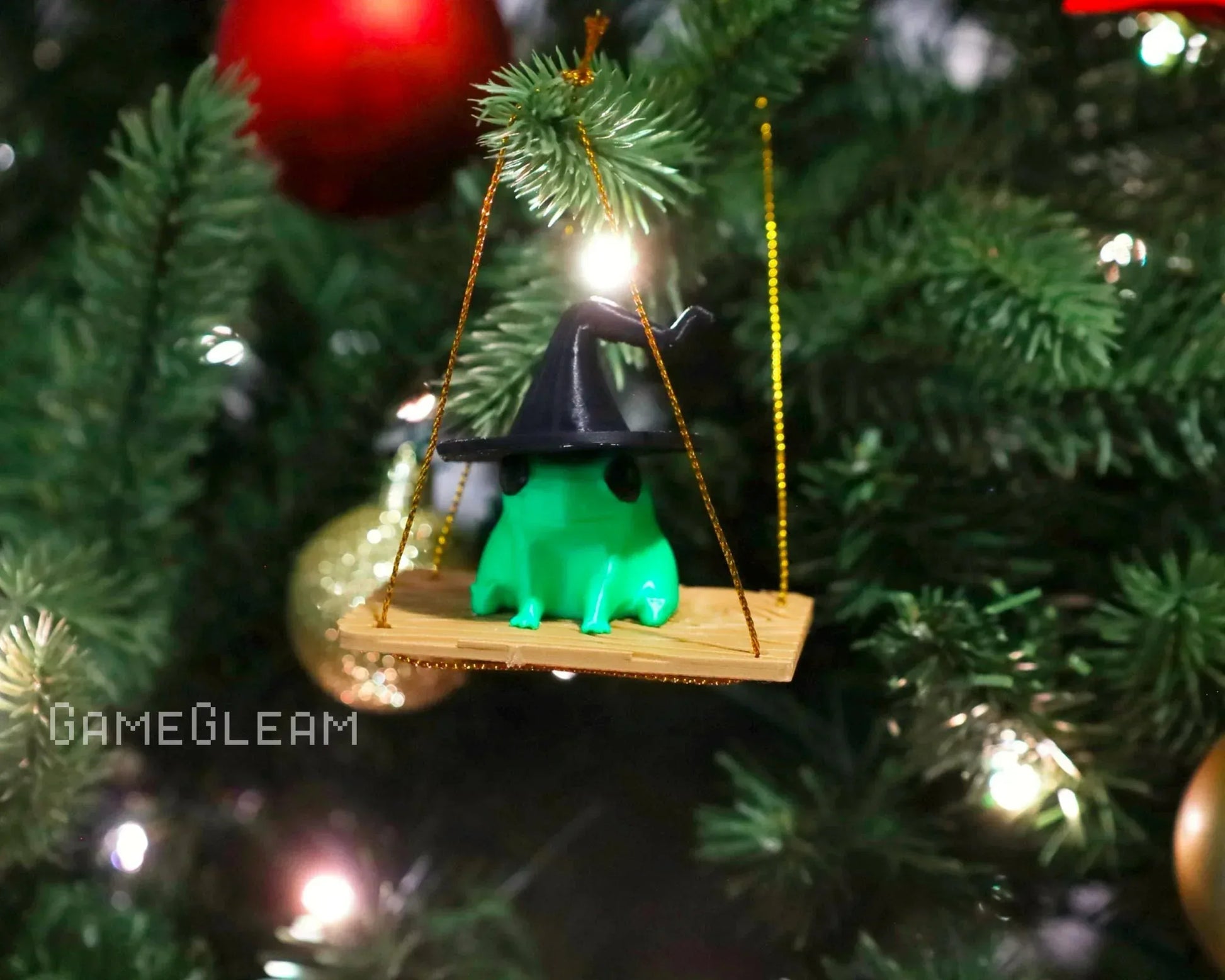 Green frog ornament with wizard hat on a wooden swing hanging from a Christmas tree