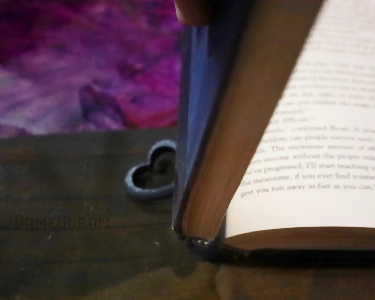 Close-up of a book with a black heart-shaped bookmark on a wooden table