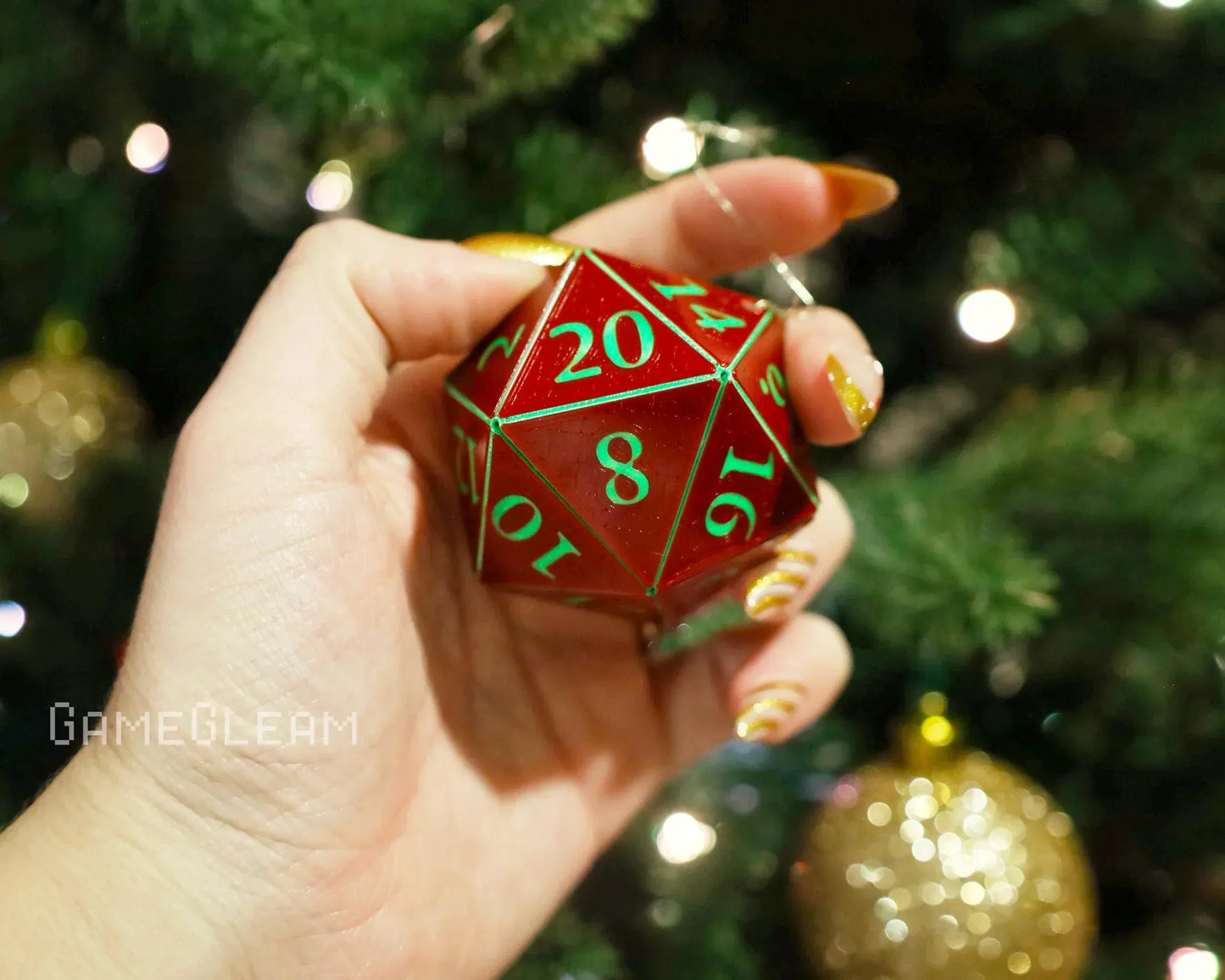 Hand holding a red and green twenty-sided dice ornament near a Christmas tree