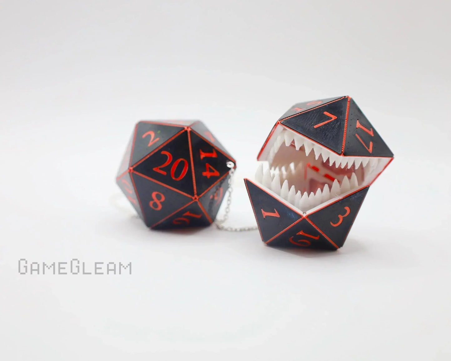 Handmade black and red 20-sided dice charm, one with monster teeth, on white background