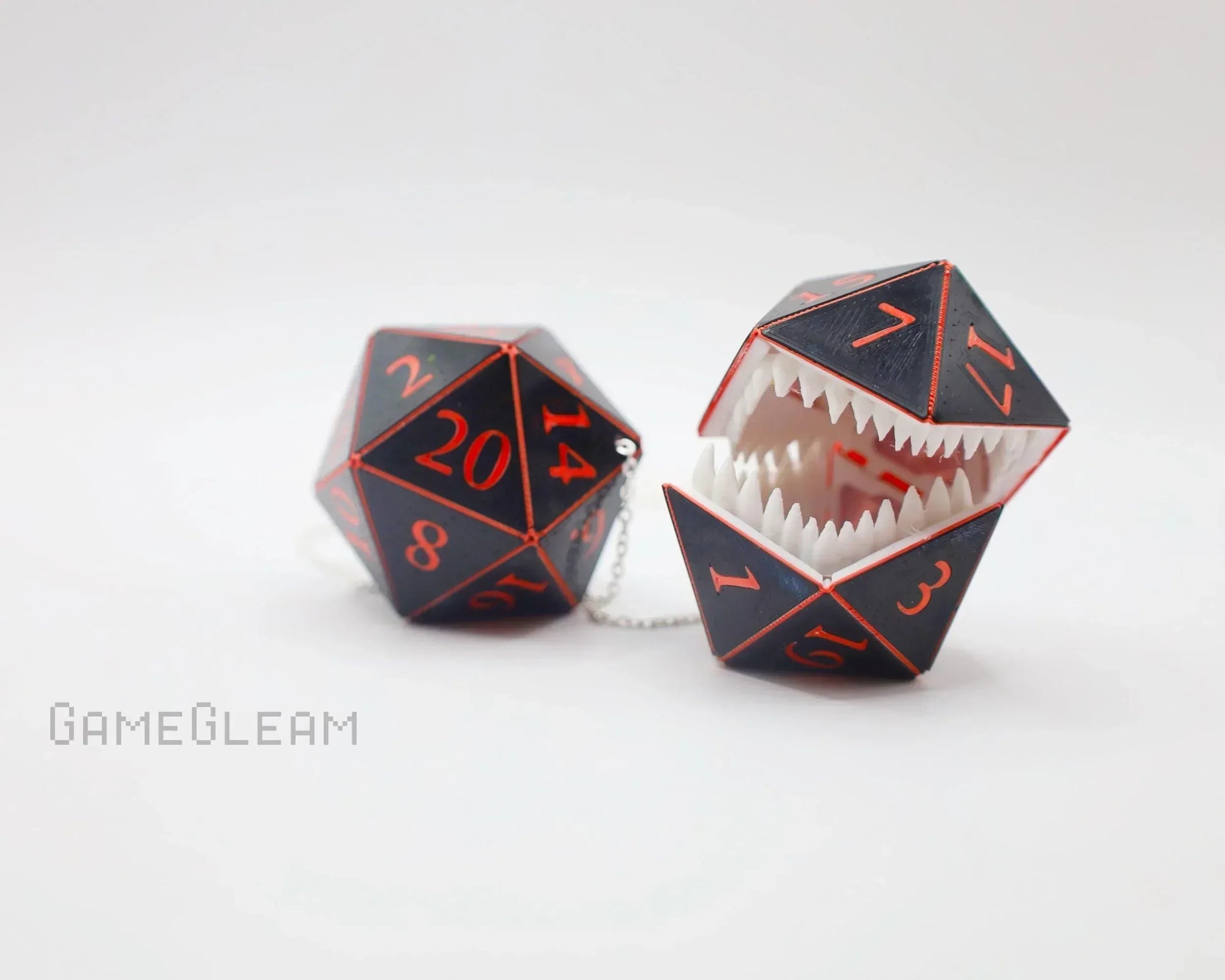 Handmade black and red 20-sided dice charm, one with monster teeth, on white background