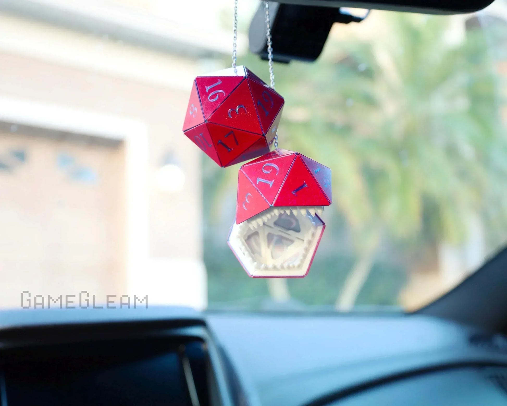 Red handmade twenty-sided dice car charm with monster mouth detail, hanging in a car