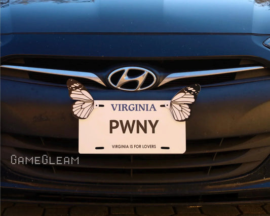 Front of a black Hyundai car with a novelty Virginia license plate, 'PWNY,' decorated with butterfly magnets.