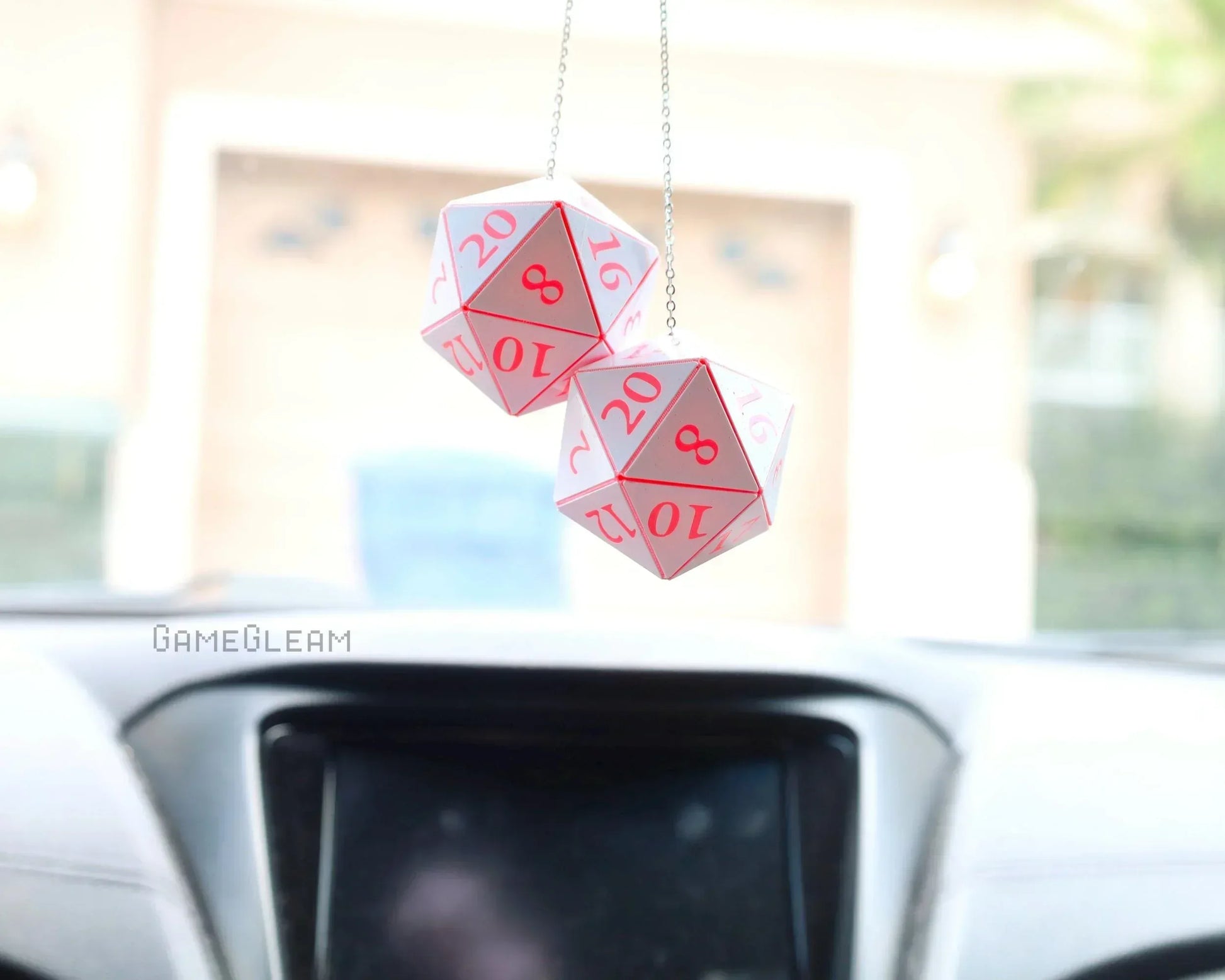 Holographic pink and white twenty-sided dice car charm hanging from a rearview mirror